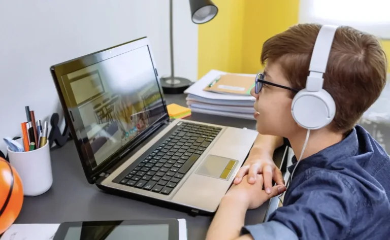A boy with headphones on looking at a laptop screen during a Chinese tuition class
